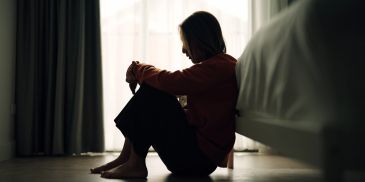 A person sitting alone on the floor in silhouette.