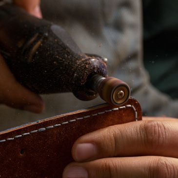 Close-up of a hand using a rotary tool on leather.