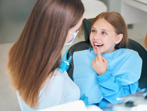 Child pointing at her teeth at the dentist.