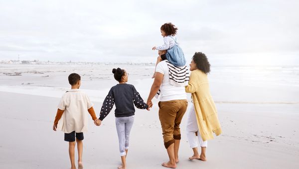 Family walking on the beach holding hands.