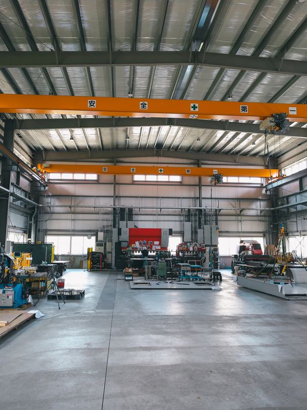 Spacious industrial workshop with cranes and machinery.