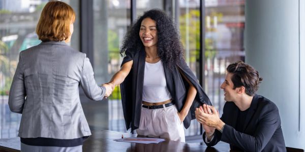 Mujer sonriente estrechando la mano en una reunión de negocios.