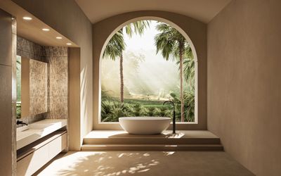 Modern bathroom with a freestanding tub and tropical view through arched window.