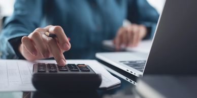 Person using calculator and laptop for calculations.