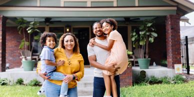 Happy family smiling in front of their home.