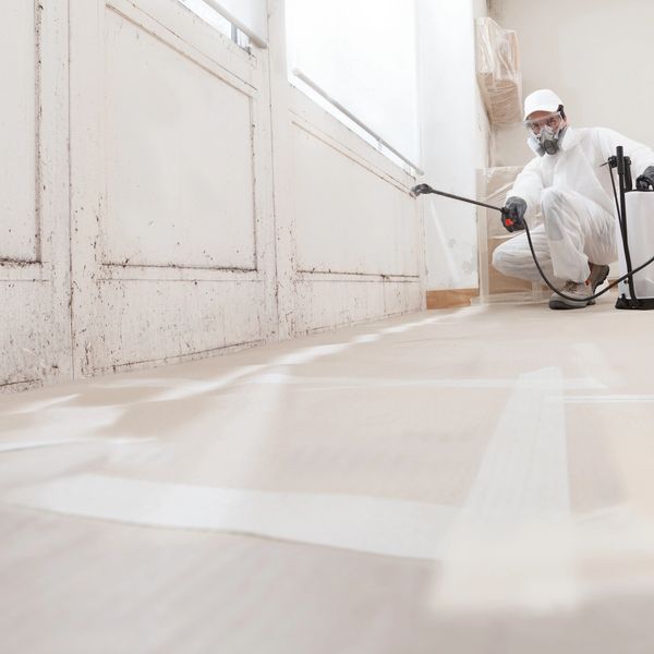 Man in protective gear disinfecting a room.