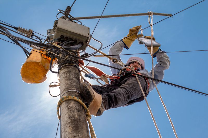 electrical technician performs maintenance to public lighting using all industrial safety elements.