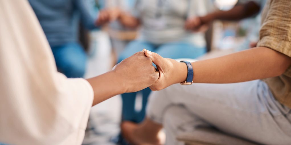 Two people holding hands in a supportive gesture.