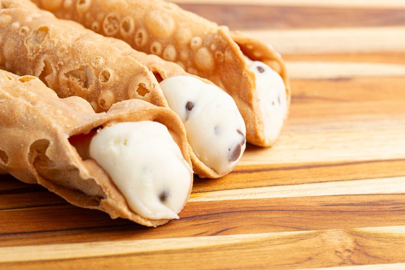 A close-up of freshly made cannoli filled with rich cream and topped with chocolate chips.