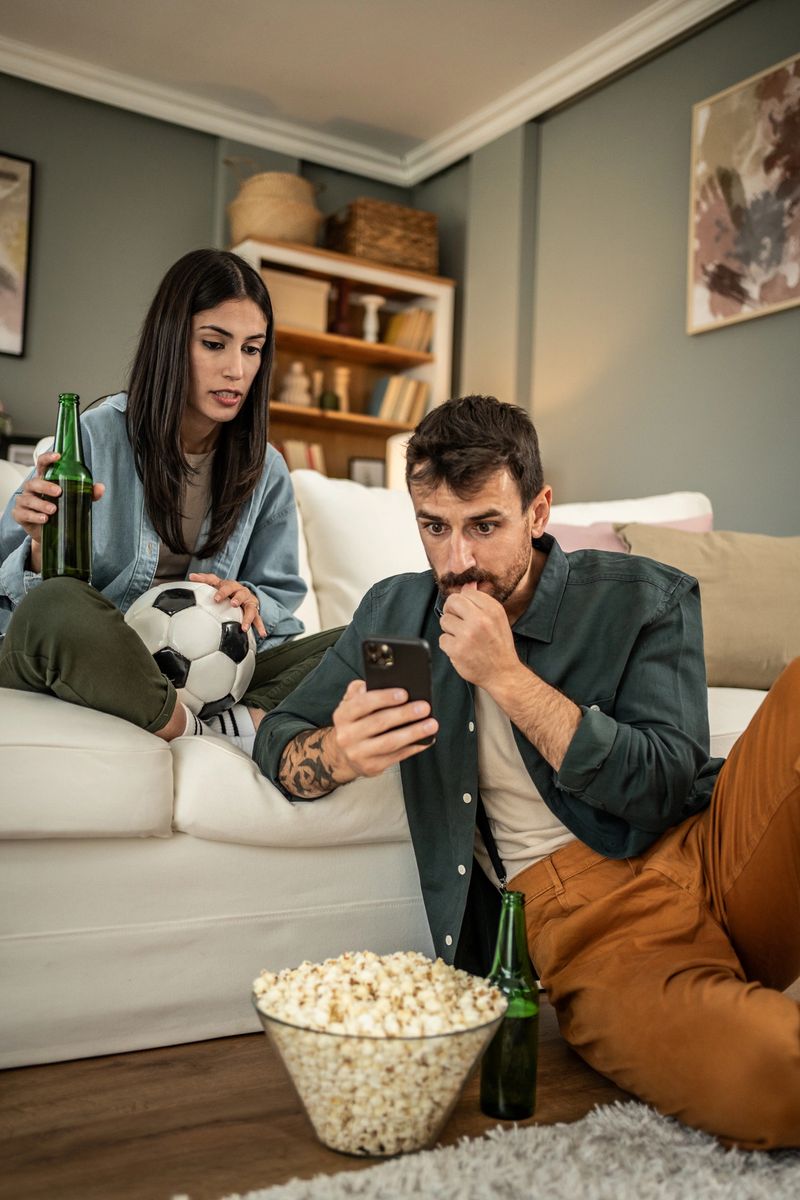 A couple watches a sports event together on the phone, tracks scores in online betting
