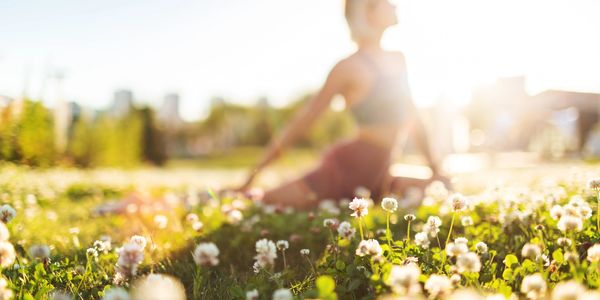 A person stretching on a sunny flower field with soft focus and warm light.