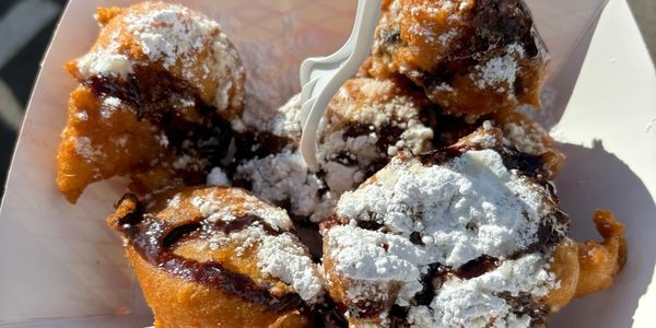 Fried dough balls topped with powdered sugar and drizzled chocolate.