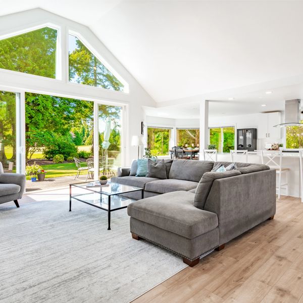 Bright modern living room with large windows and gray furniture.