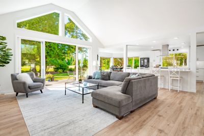 Bright modern living room with large windows and gray furniture.