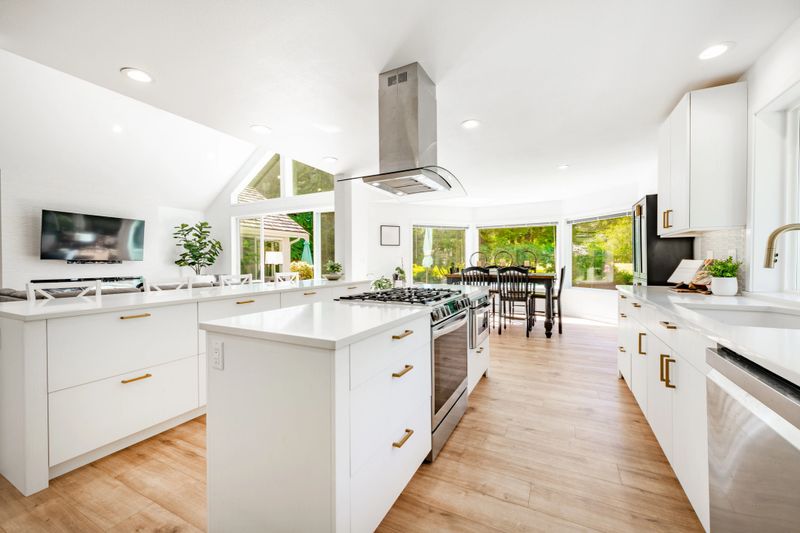 This home has large open concept room painted white with simple and stylish decor. The kitchen has expansive countertops and cupboards and cabinets with gold fixtures. Living room has wall mounted tv and an electric fireplace, the family room has 2 blue recliners and a wood burning fireplace. Rooms have multiple large windows with views to the garden and golf course beyond the backyard. Lush landscaping with mature trees. Bathroom is sparkling clean and white marble with free standing bath tub and open glass wall shower with gold fixtures.