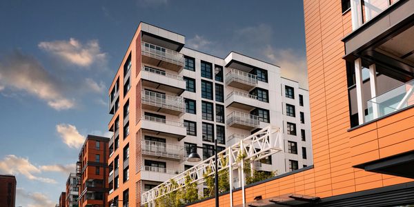 Modern apartment buildings with orange and white panels under a cloudy sky.