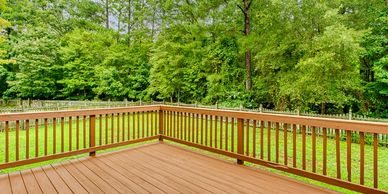Spacious wooden deck overlooking a lush green backyard with trees.