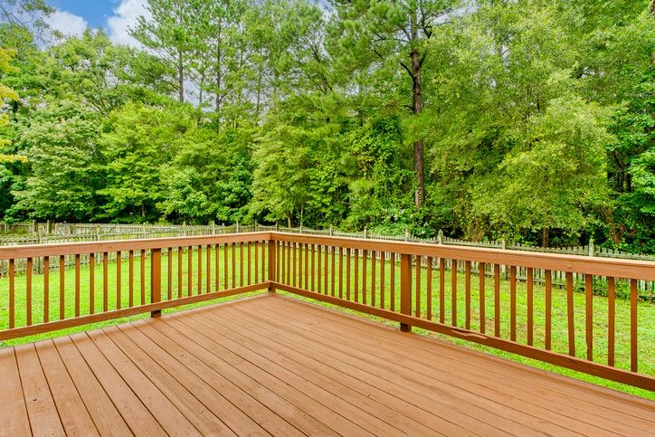 Beautifully constructed wooden deck with railings overlooking a lush backyard