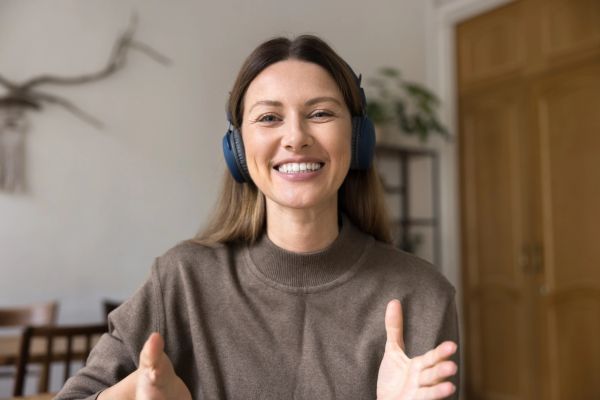 Woman wearing headphones smiling and gesturing.