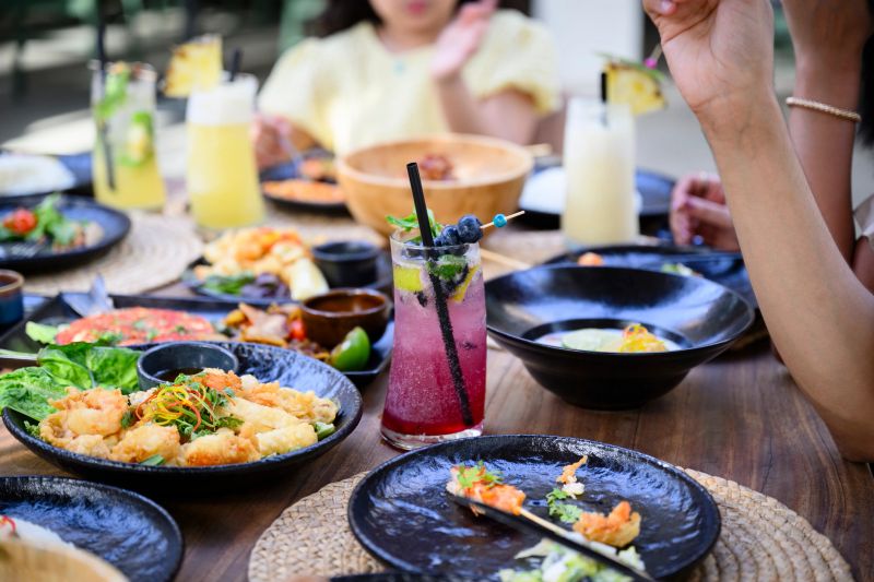 Focus on platters of seafood and refreshment as vacationers enjoy afternoon meal.