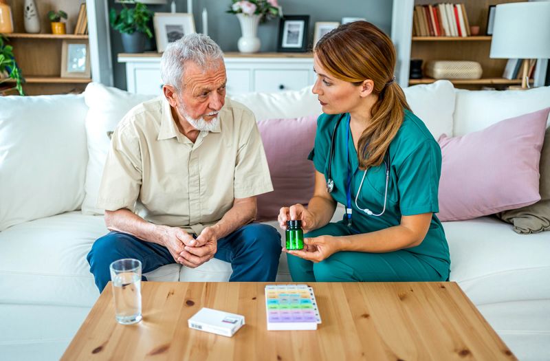 Female home nurse helping senior man to organize medication during a home visit