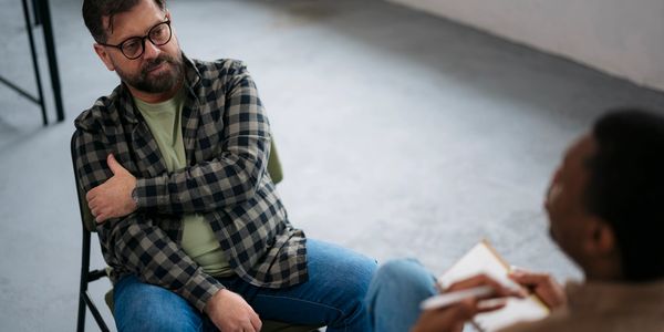 Man in a therapy session, appearing thoughtful.