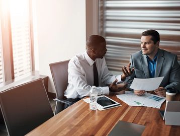 Two businessmen discussing documents in a modern office.
