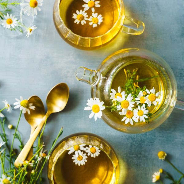 Herbal tea in a tea cup on a table with flowers in it.