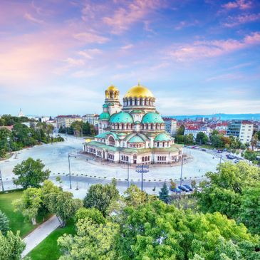 The Alexander Nevsky Cathedral with golden domes under a pink and blue sky.