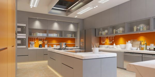 Modern kitchen with gray cabinets and orange backsplash, featuring a large island and bright lighting.