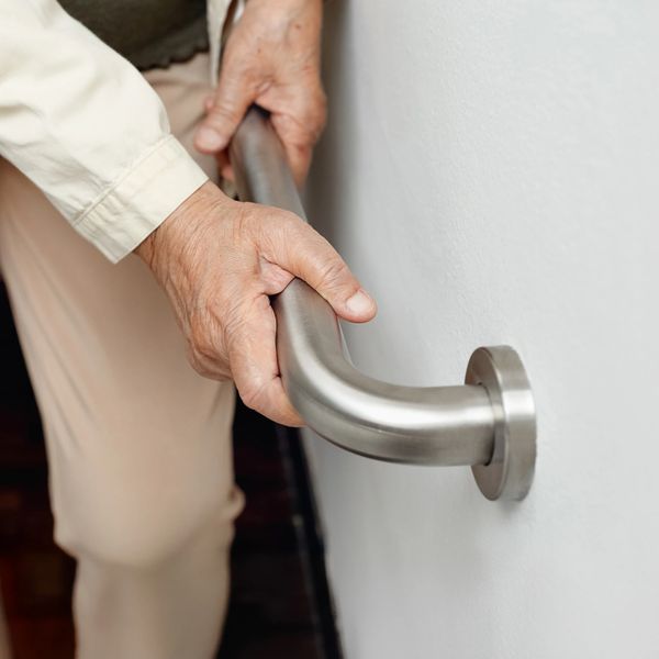 An elderly person gripping a metal handrail for support.