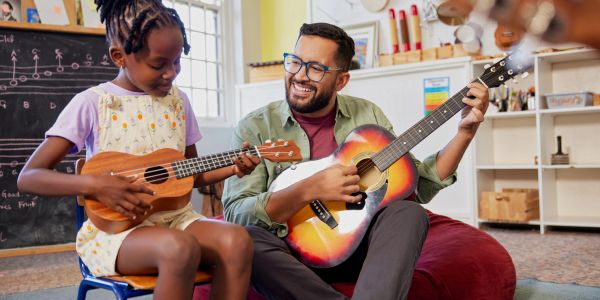 Çocuk ve yetişkin ukulele ve gitar çalıyor.