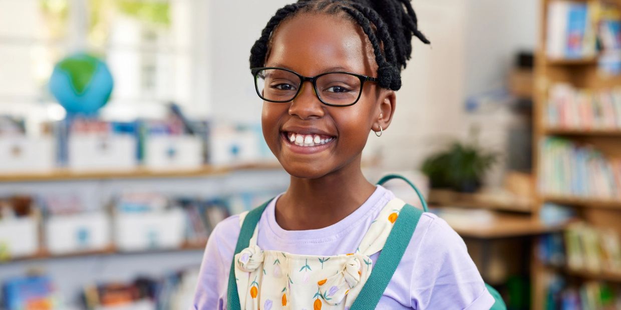Smiling schoolgirl with glasses in classroom.