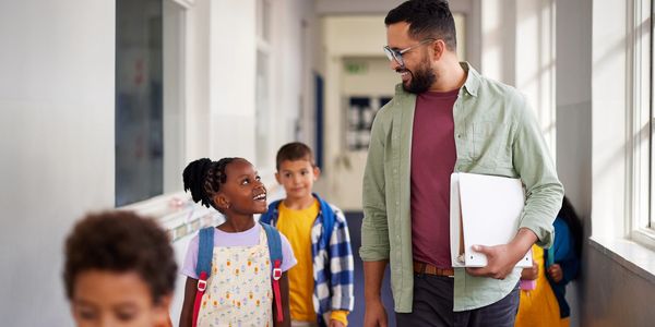 Teacher walking down a hallway with smiling students.
