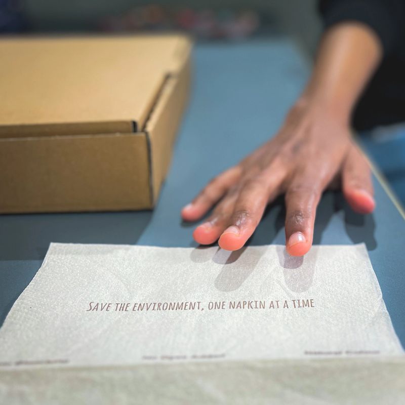A woman reaching out to take a sustainable and biodegradable napkin to ensure the safety of the environment