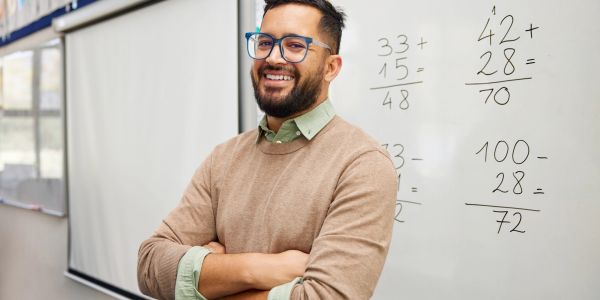 Man smiling in front of math problems on a whiteboard.