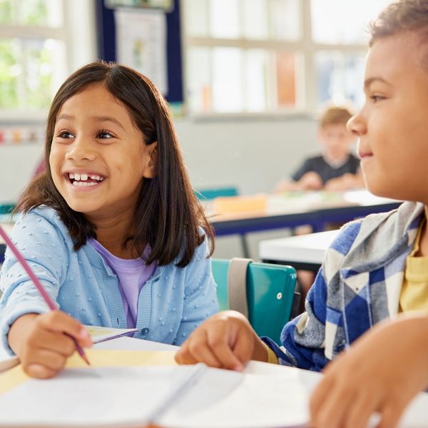 Young girl smiling and holding a pencil.