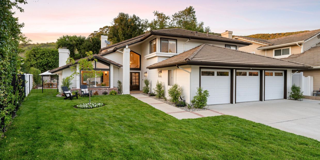 Modern two-story house with a manicured lawn and triple garage.