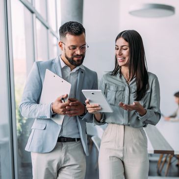 Two colleagues discussing work using a tablet in a modern office.