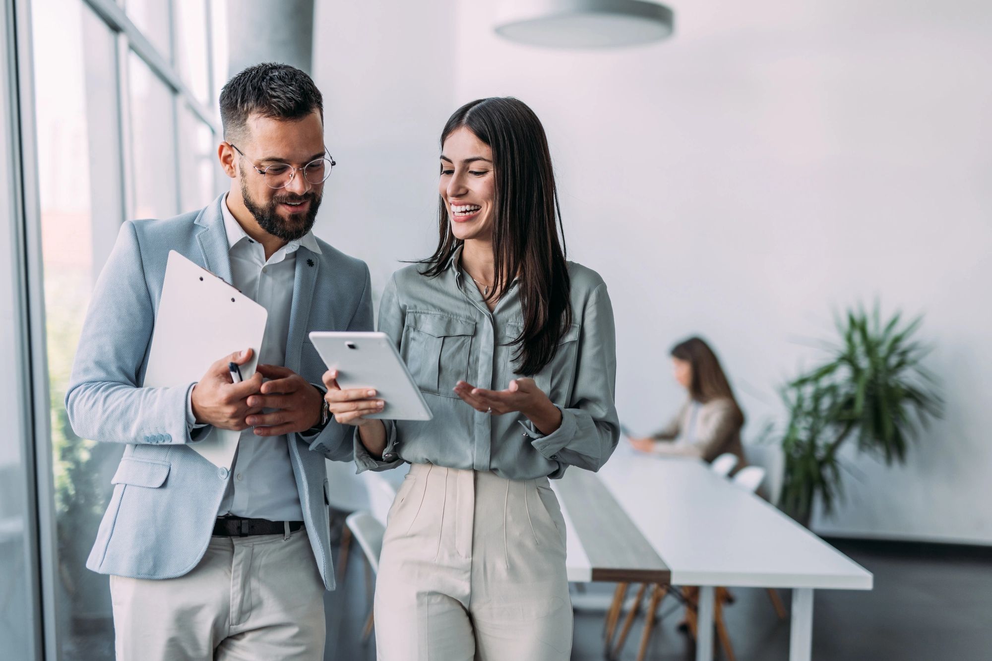 Professionals collaborating on a tablet in a modern office, discussing AI-powered grant writing

