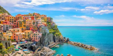 Colorful houses on a seaside cliff with turquoise waters.