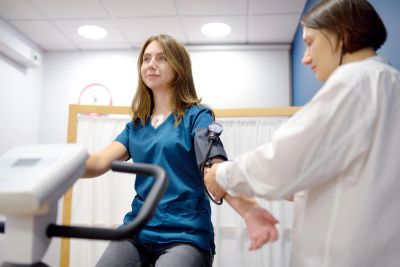 A woman getting her blood pressure checked while exercising on a stationary bike.
