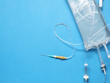 IV drip bag with tubing and needle on a blue background.