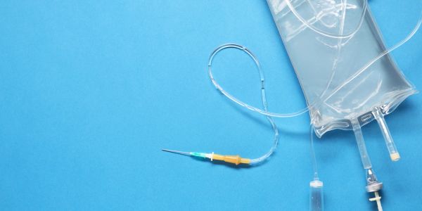 A medical IV device with a neutral blue background.