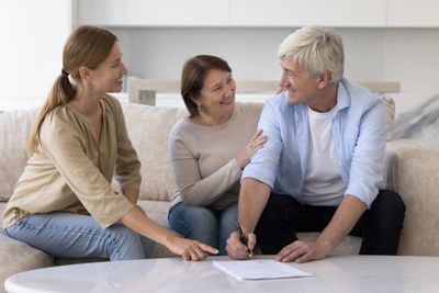 Three adults happily discussing while signing a document at home.