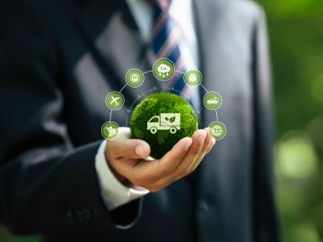 Businessman holding a green energy concept sphere with renewable energy icons.