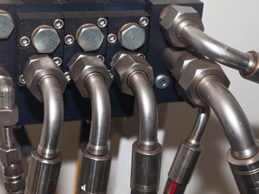 Close-up of metal hydraulic pipes connected with large nuts.