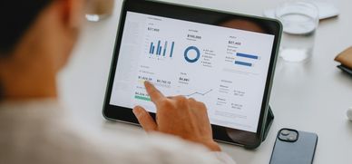 Person analyzing financial data on a tablet with charts and graphs.