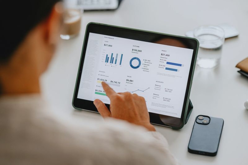 Close-up of business analyst reviewing financial data on tablet in office, demonstrating the use of technology in modern business environments.