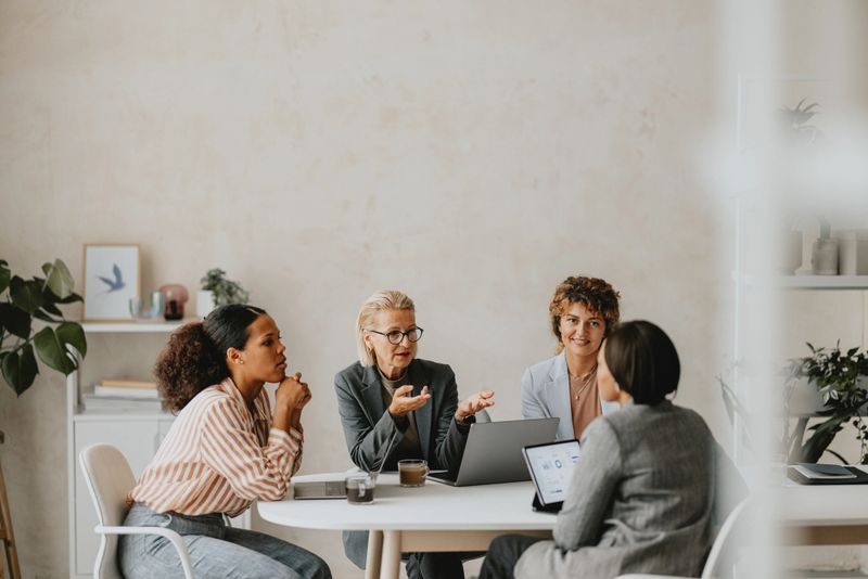 A diverse group of business professionals engaged in a meeting at a modern office, discussing strategies and planning.